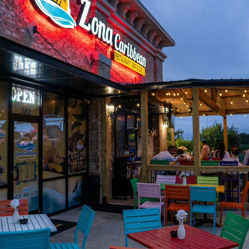 Tona Caribbean restaurant exterior at dusk, featuring a string-lit covered patio, colorful outdoor furniture, and diners.
